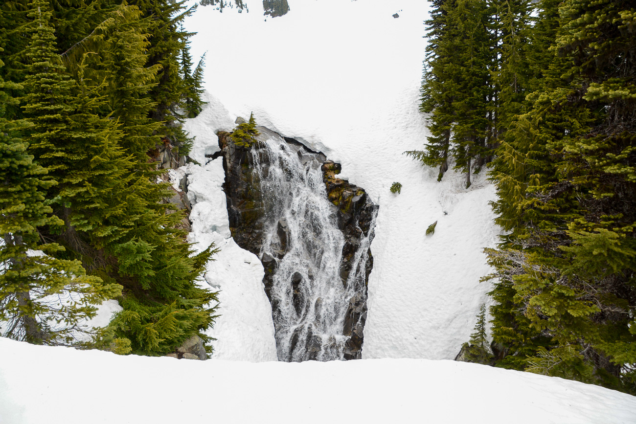 Wasserfall im Tiefschnee mit Nadelbäumen zu beiden Seiten