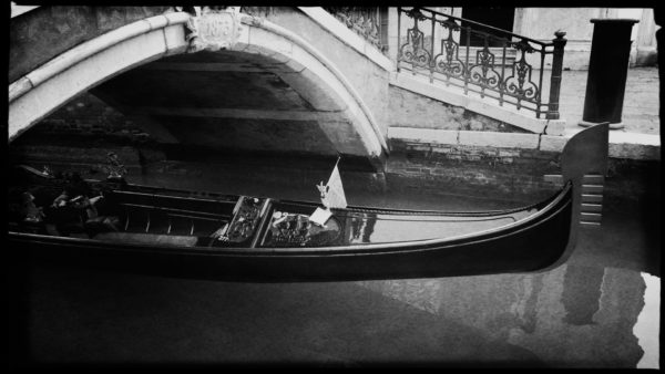 Gondel kommt unter einer Brücke in Venedig hervor