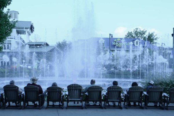 Einträchtig betrachten genügsame Amerikaner in Adirondack-Stühlen einen Springbrunnen