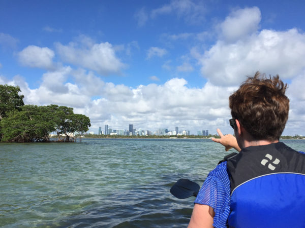 Eine Frau zeigt aus einen Kanu auf die Wolkenkratzer von Miami