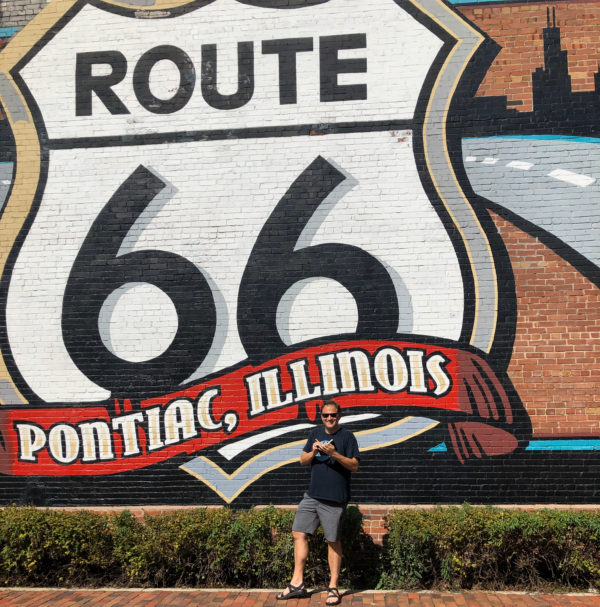 Autor Ralf Johnen vor einem Wandgemälde mit dem Logo der Route 66 in Illinois