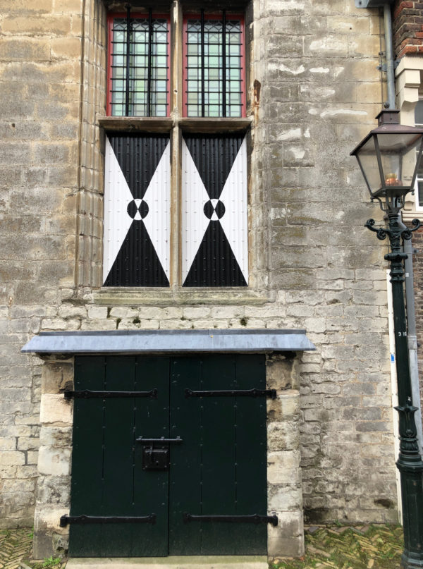 Details eines alten niderländischen Rathauses mit farbigen Fensterläden und alter Laterne