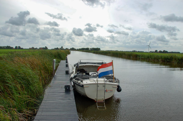 Bootsanleger mitten in der Natur Frieslands mit Kanal und Windrad