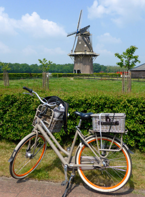 Ein Fahrrad mit Picknickkorb vor einer Windmühle während der Radtour durch Overijssel