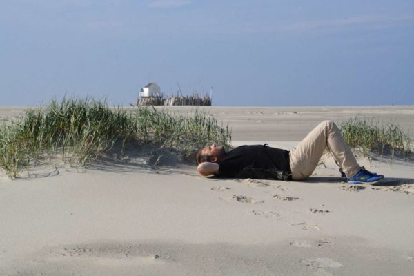 Autor Ralf Johnen liegt im Sand auf Vlieland