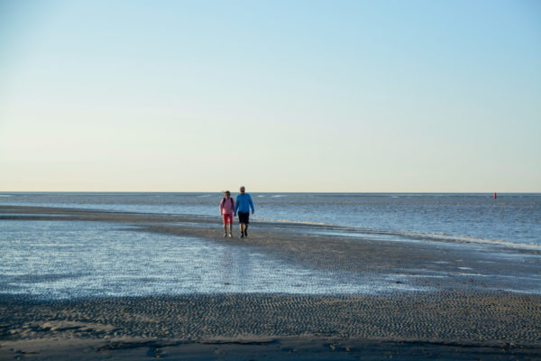 Ein Paar vergnügt sich im Wattenmeer bei einer Wanderung