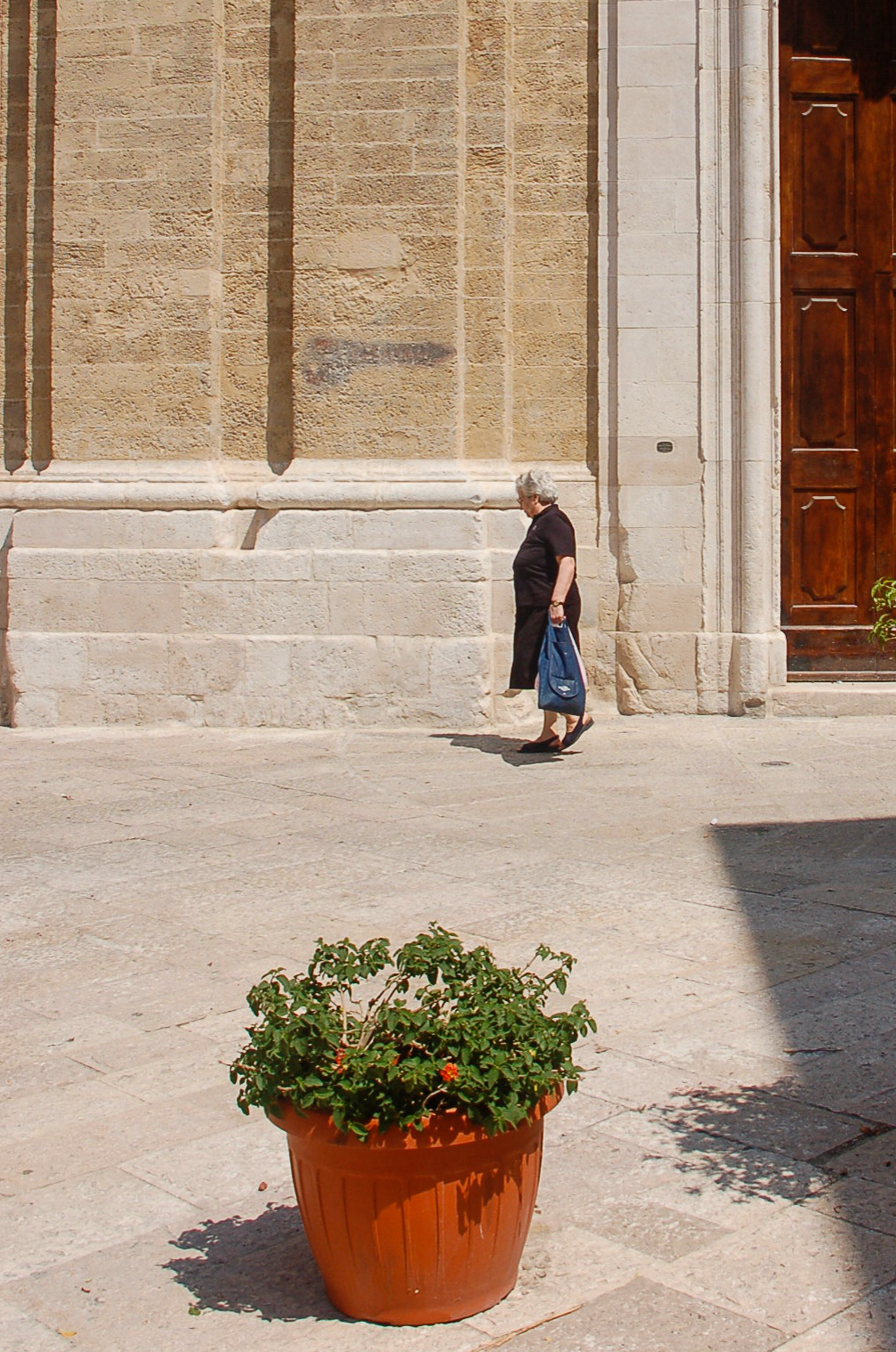 Eine Frau vor der Kirche von Bari mit Blumentopf