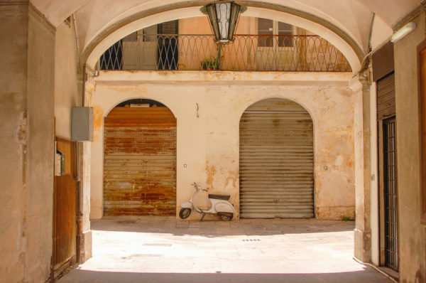 Häuser mit Arkaden und Vespa in der süditalienischen Stadt Lecce