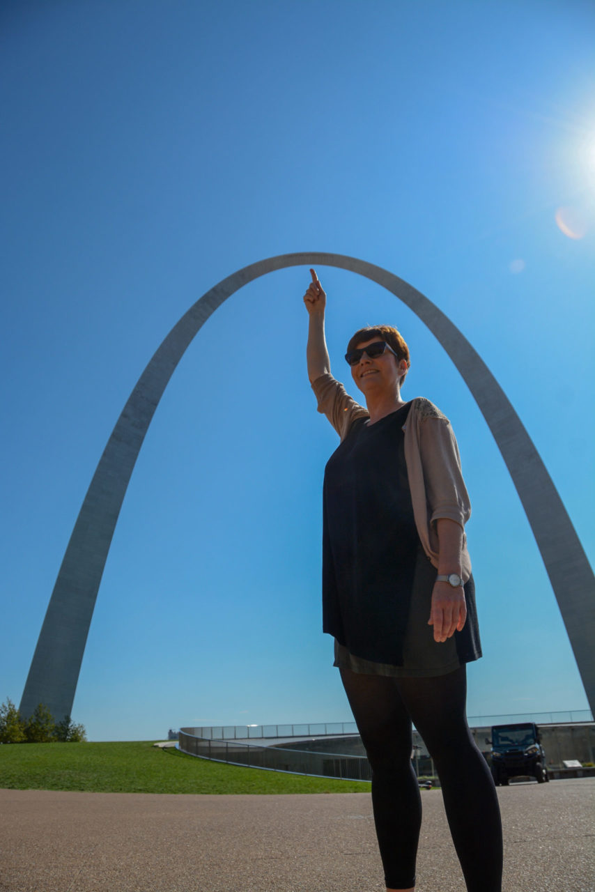 Junge Frau deutet mit dem Finger auf den Gateway Arch in Saint Louis