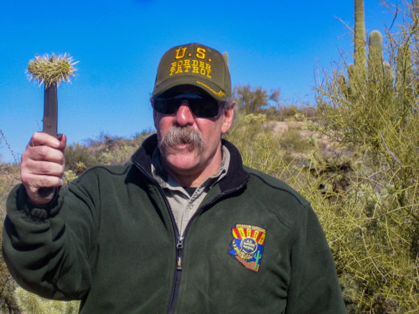 Ein Mann mit einem Messer und einem Stück Kaktus im Ornat der US Border Patrol
