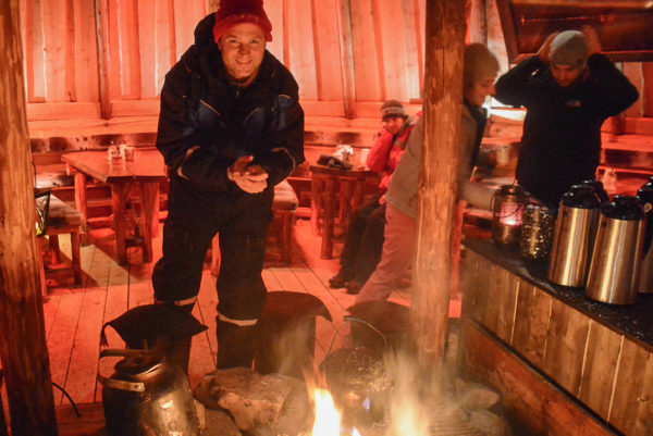 Autor Ralf Johnen wärmt sich die Hände am Feuer in einer Hütte in Norwegen