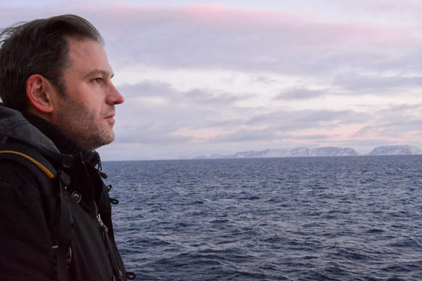 Autor Ralf Johnen blickt versonnen in die Landschaft bei seiner Tour mit Hurtigruten im Winter