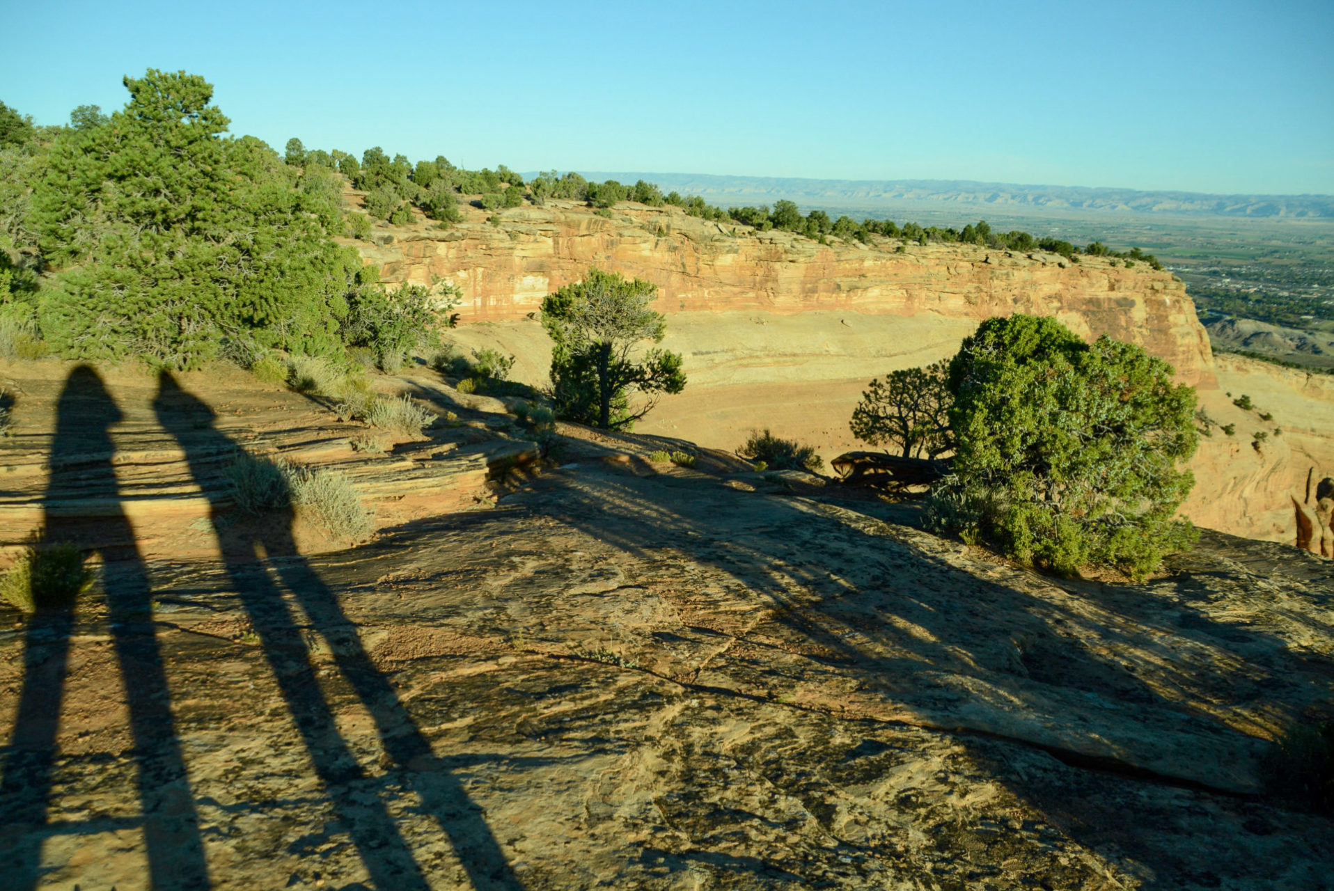Lange Schatten am Colorado National Monument mit Fluss und Tal in der Ferne