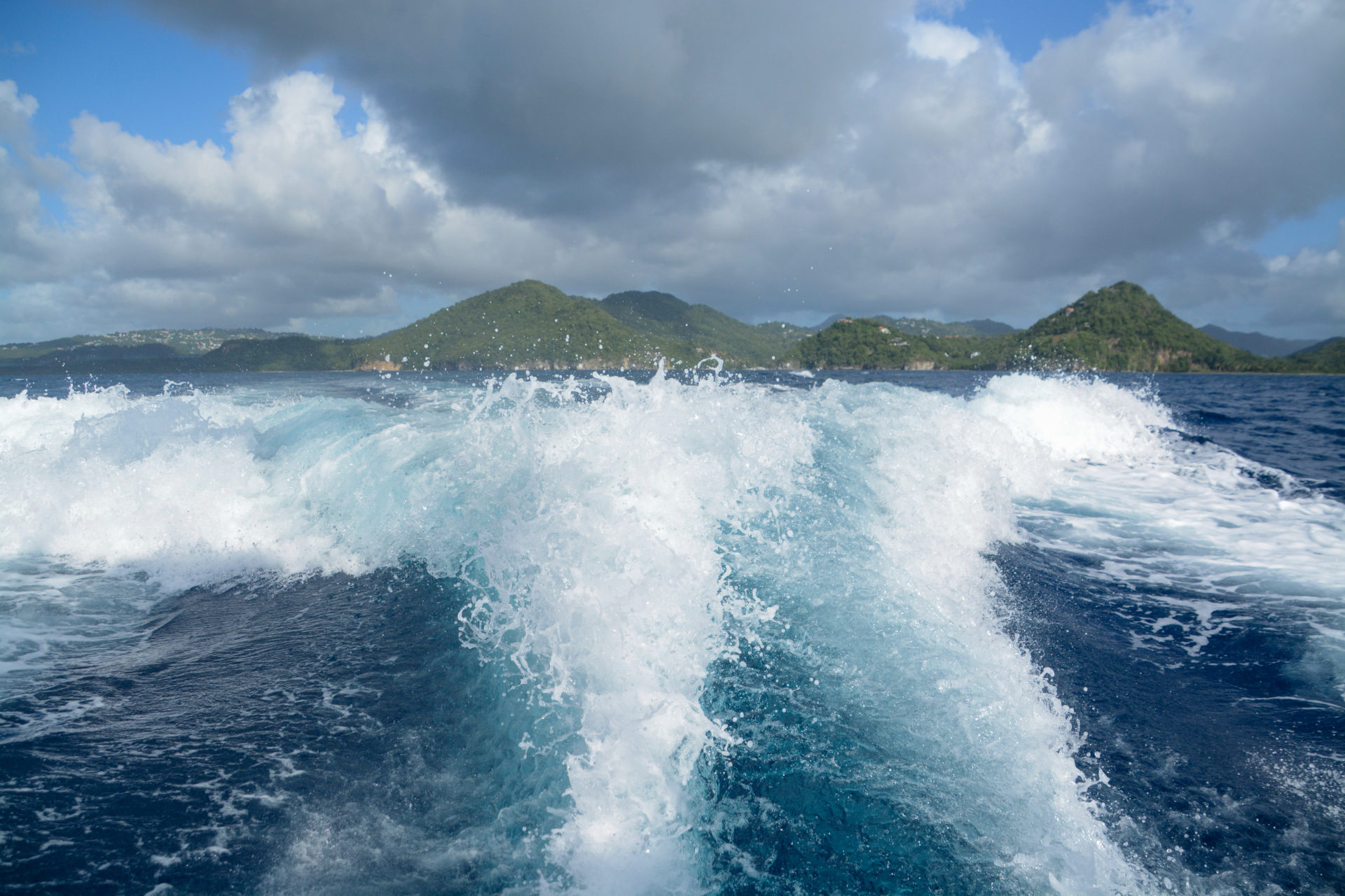 Aufgewühltes Wasser hinter einem Boot mit Blick auf das Festland von Saint Lucia