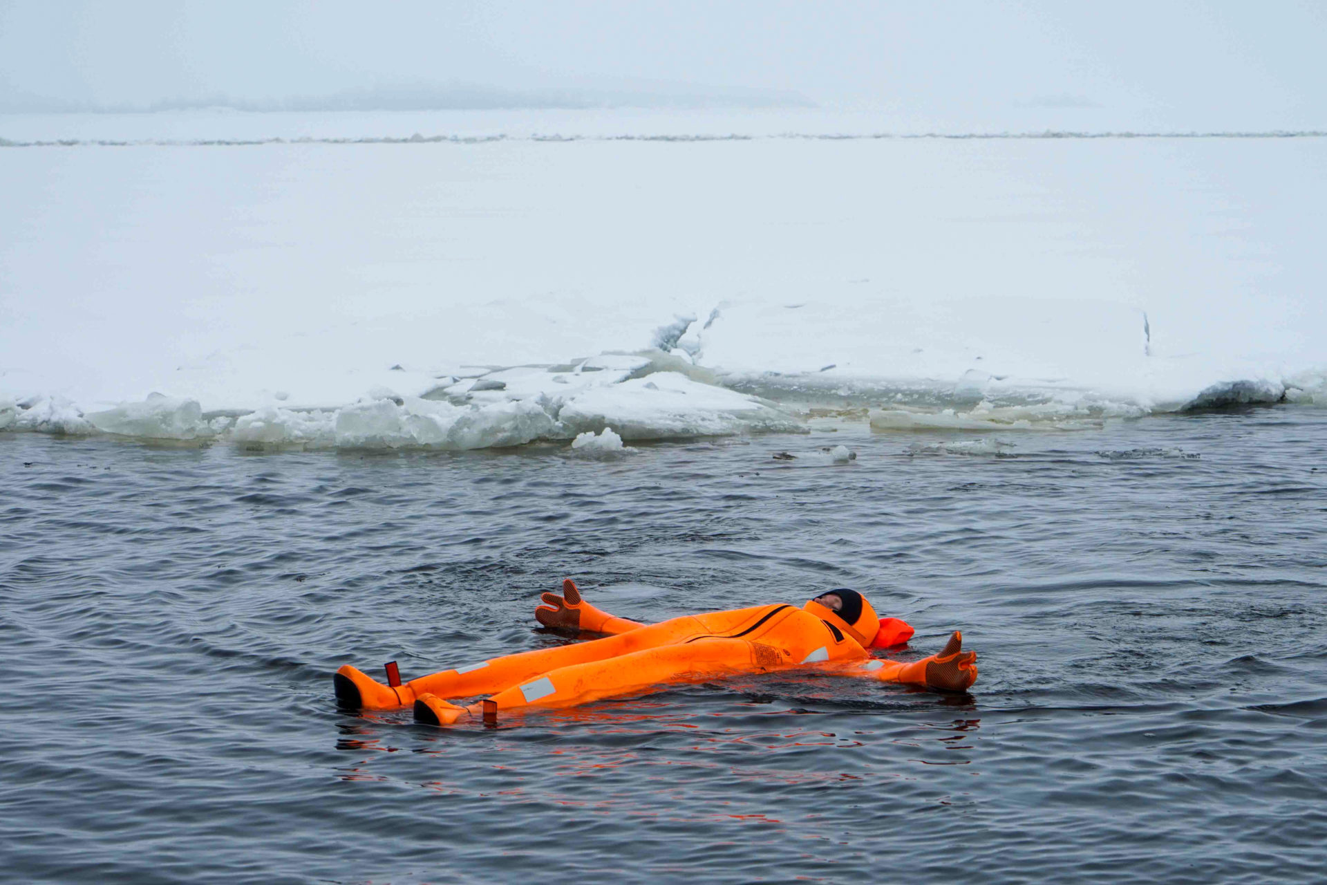 Ein Passagier im Thermoanzug treibt im eiskalten finnischen Wasser