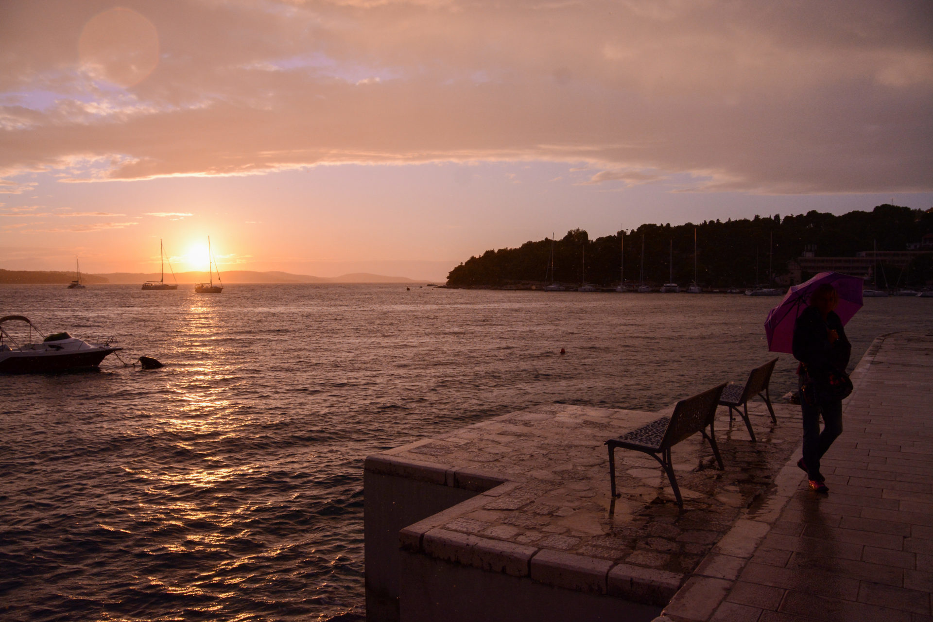 Person mit Regenschirm auf der kroatischen Insel Hvar im Sonnenuntergang