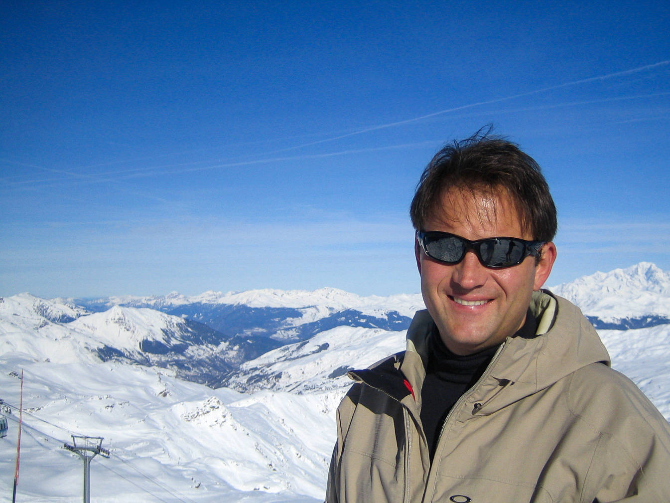 Autor Ralf Johnen vor Kabinenbahn mit Alpenpanorama auf einem Berg in Val Thorens