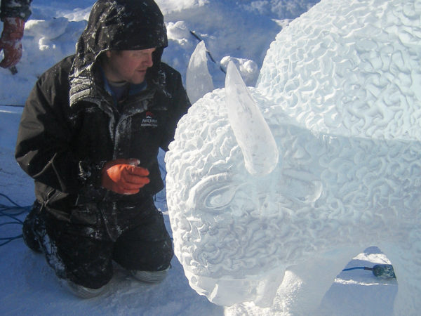 Mann arbeitet an der Eisskulptur eines Büffels beim Ice Magic Festival in Lake Louise
