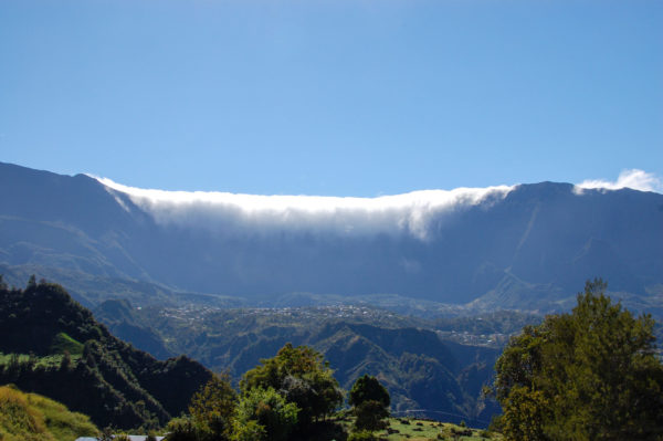 Wolken strömen über den Piton des Neiges auf La Réunion und scheinen ins Tal zu stürzen