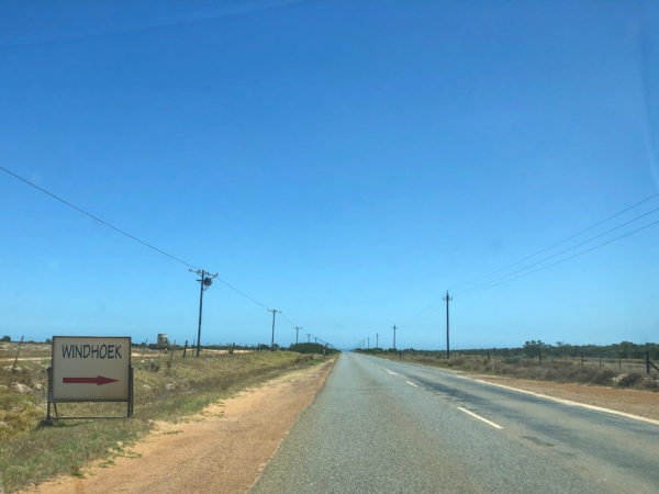 Autolose Straße in Südafrika mit handbemaltem Schild in Richtung Windhoek