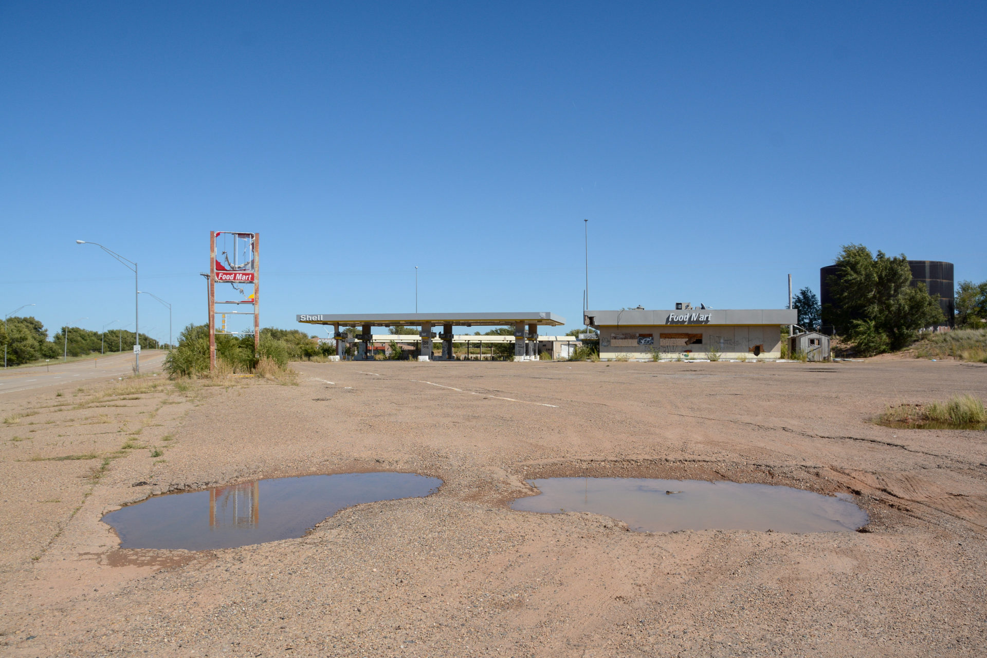 Zwei Wasserlöcher vor einer verlassenen Tankstelle von Shell in Tucumcari