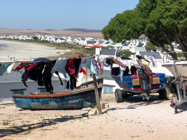 Boote und eine Wäscheleine vor den weissen Häusern von Paternoster in Südafrika
