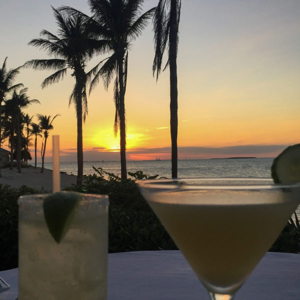 Cocktails während des Sonnenuntergangs auf Sunset Key in Florida mit Segelboot im Hintergrund
