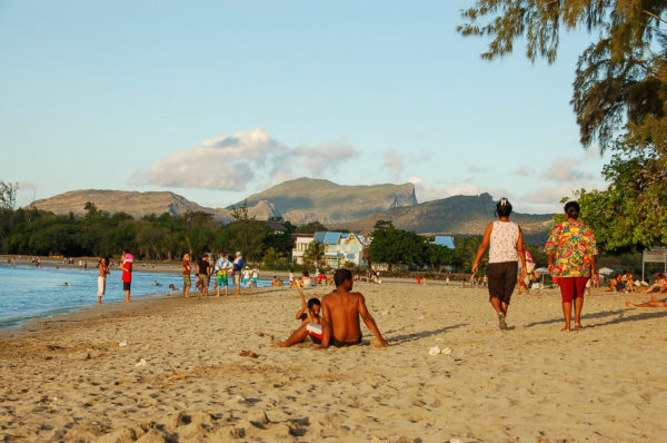 Menschen am Strand vor Bergen am Tamarin Beach im Westen von Mauritius