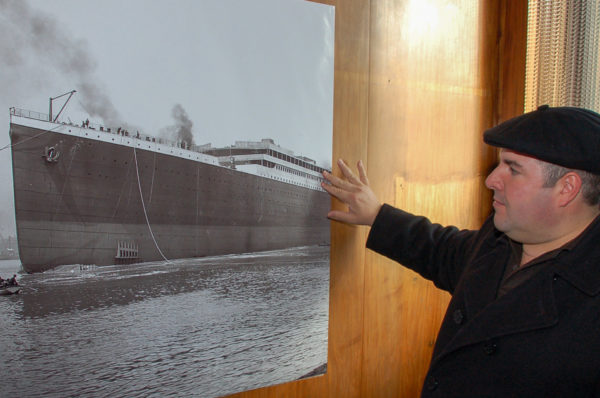 Tour-Guide Richard Cobb vor einem Foto der Titanic in der Werft von Harlett and Wolff in Belfast