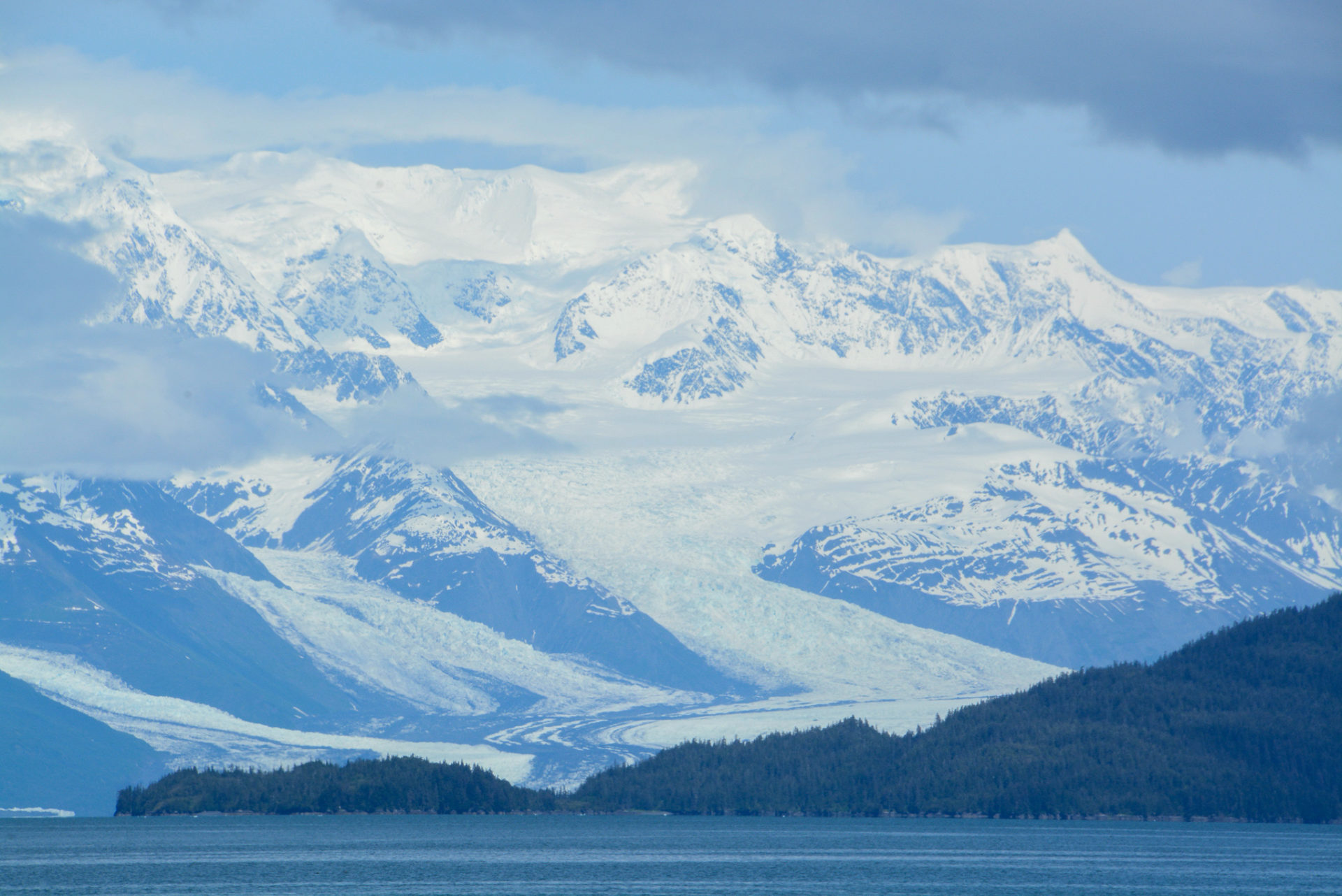 Kontrast zwischen schneebedeckten Bergen und grünen Hügel im Prinz-William-Sund in Alaska