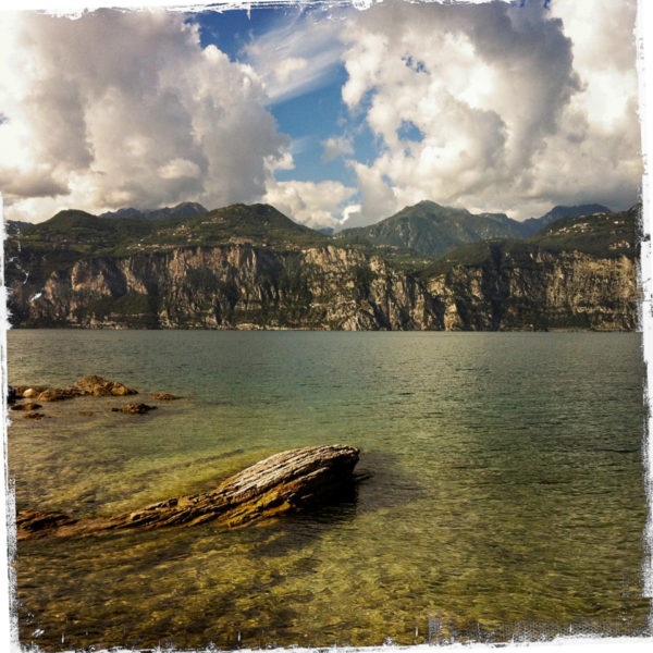 Felsige Küste am Gardasee in Italien mit Wolkengebirgen und Bergen