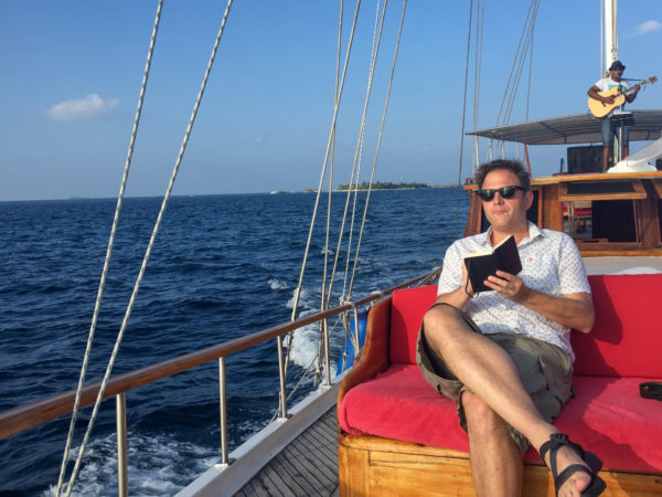 Mann mit Notizbuch auf einem Boot des Mirihi Island Resort