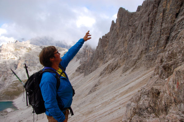 Bergführer Herbert Summerer von der Alpinschule Sexten zeigt auf einen Vogel in einer Bergwand