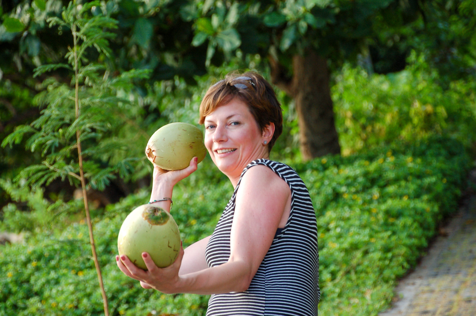 Frau wirft an einem Strand in Thailand mit Kokosnüssen
