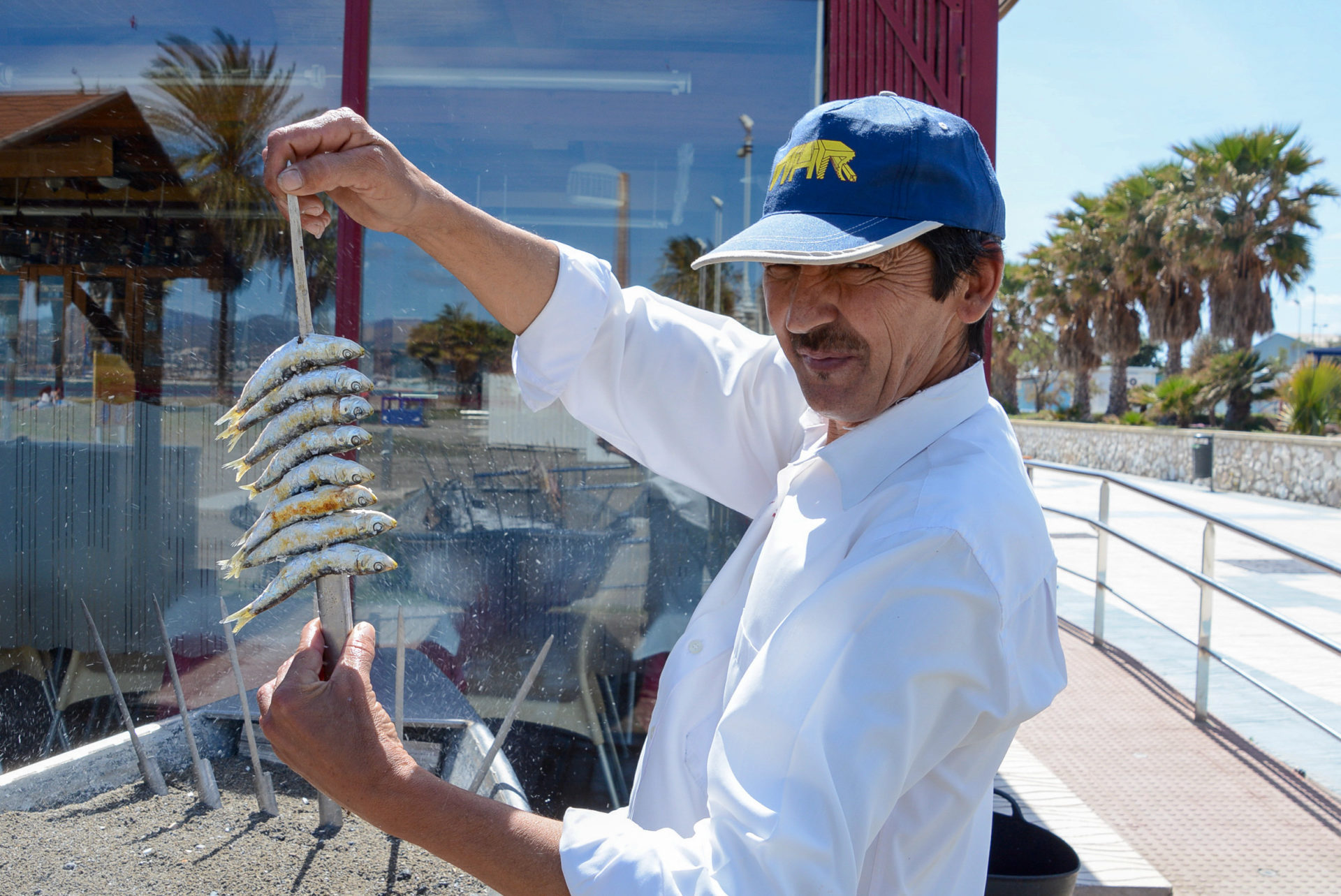 Mann spießt Sardinen auf in einem Chiringuito in Andalusien