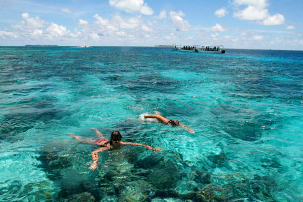 Schnorchler an einem Korallenriff bei Palau mit Booten im Hintergrund