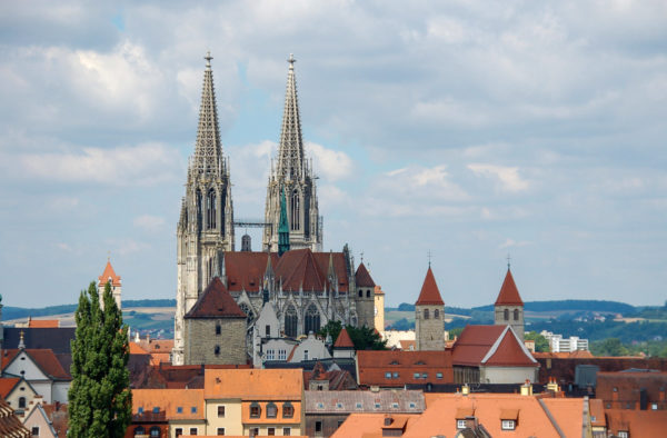 Der Dom von Regensburg umgeben von Türmen und sanften Hügeln im Hintergrund