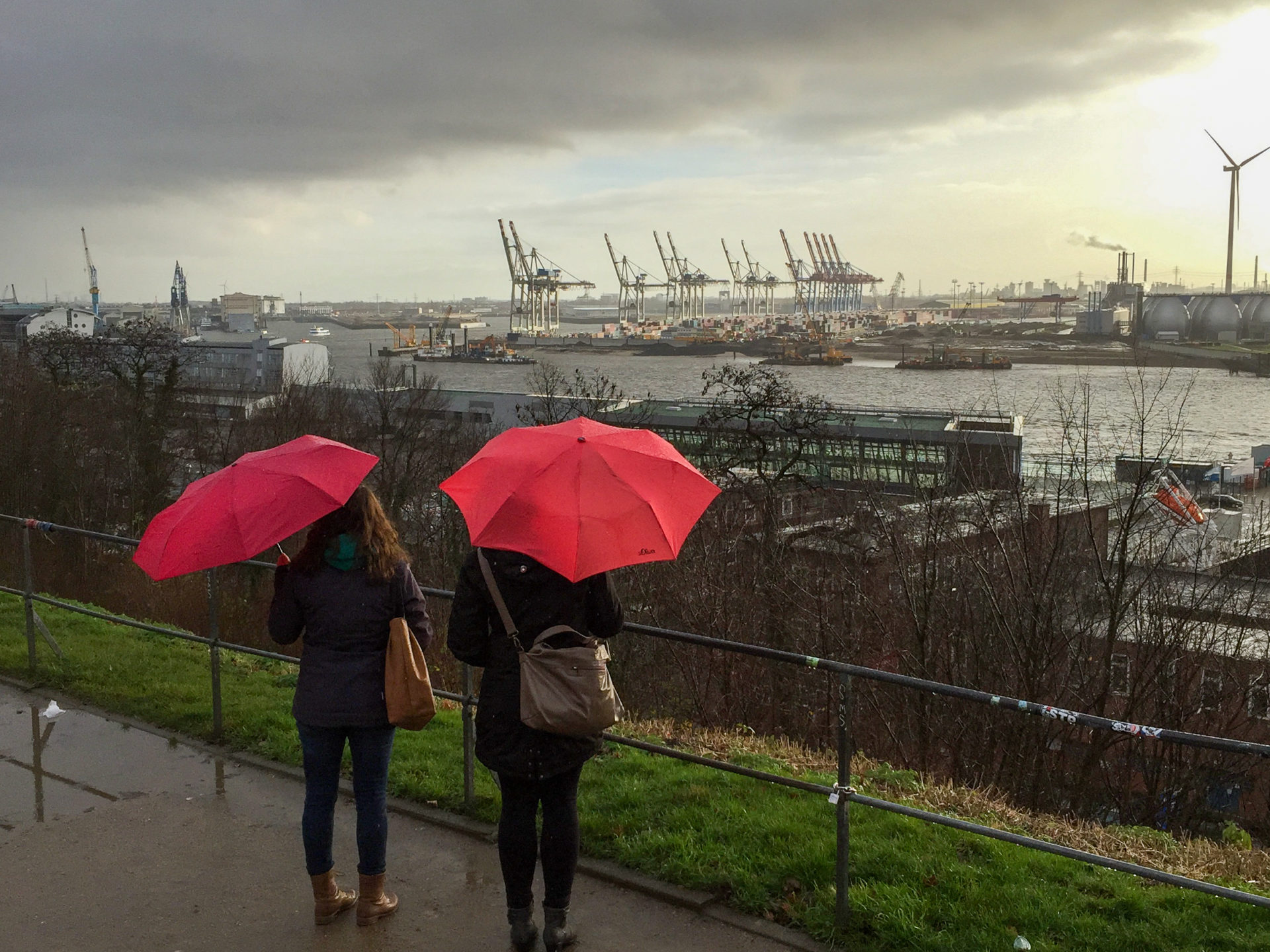 Zwei Frauen mit roten Regenschirm blicken von Altona aus auf den Hamburger Hafen