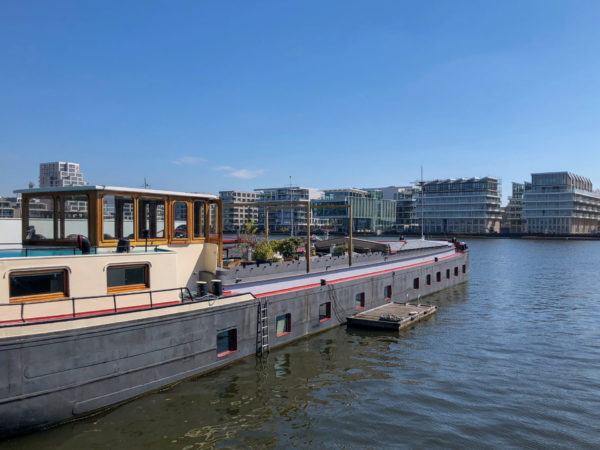 Wohnboot mit modernen Gebäude auf dem Cruquiuseiland im Amsterdamer Hafen