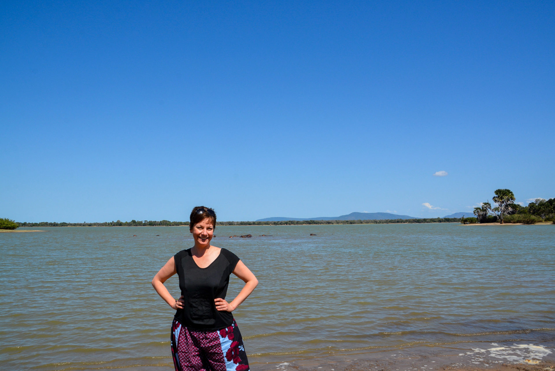 Autorin Alexandra Johnen am Ufer eines Flusses, in dem sich Nilpferde aufhalten