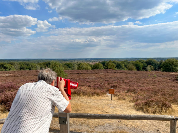 Autor Ralf Johnen blickt durch ein Fernrohr auf die Heide des Sallandse Heuvelrug