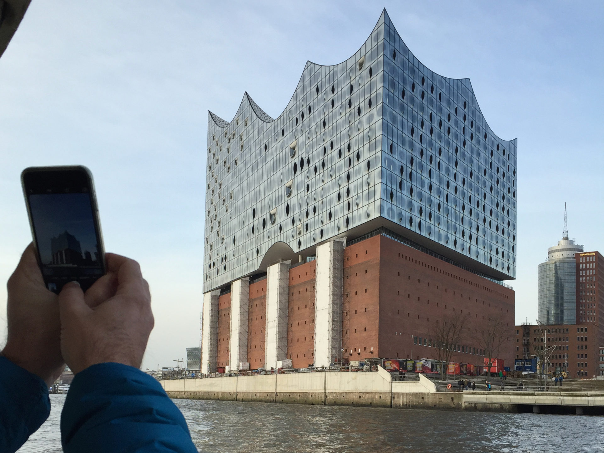 Mann fotografiert die Elbphilharmonie in Hamburg mit seinem Handy
