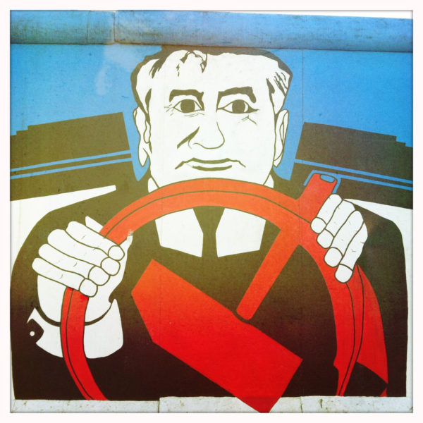 Mural von Gorbatschow hinter einem Steuer aus Hammer und Sichel in Berlin