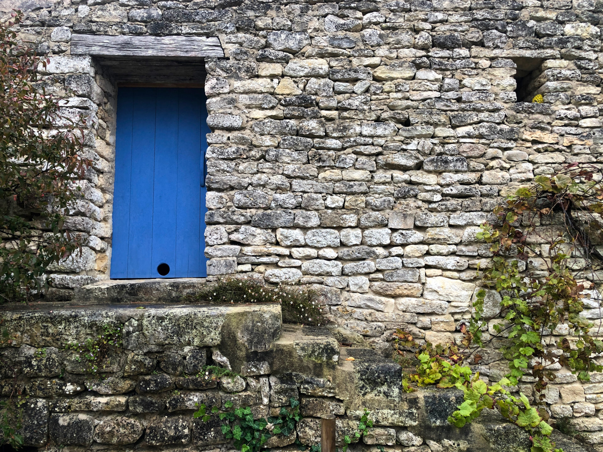 Stilleben mit Steinmauer und blauer Türe in La Cotinière an der französischen Atlantikküste