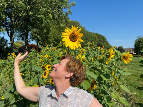 Junge Frau posiert vor einem Sonnenblumenfeld im Rivierenland