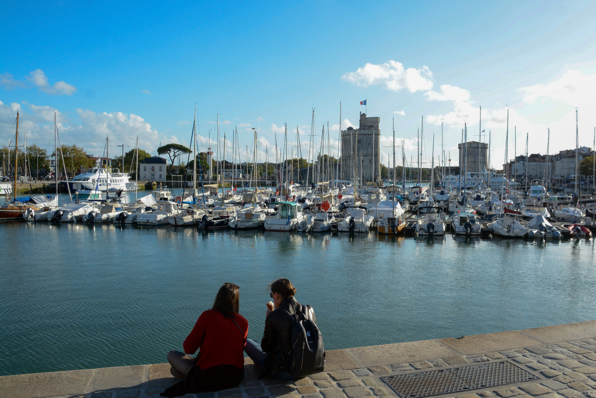 Zwei junge Frauen essen ein Eis auf der Hafenmauer von La Rochelle
