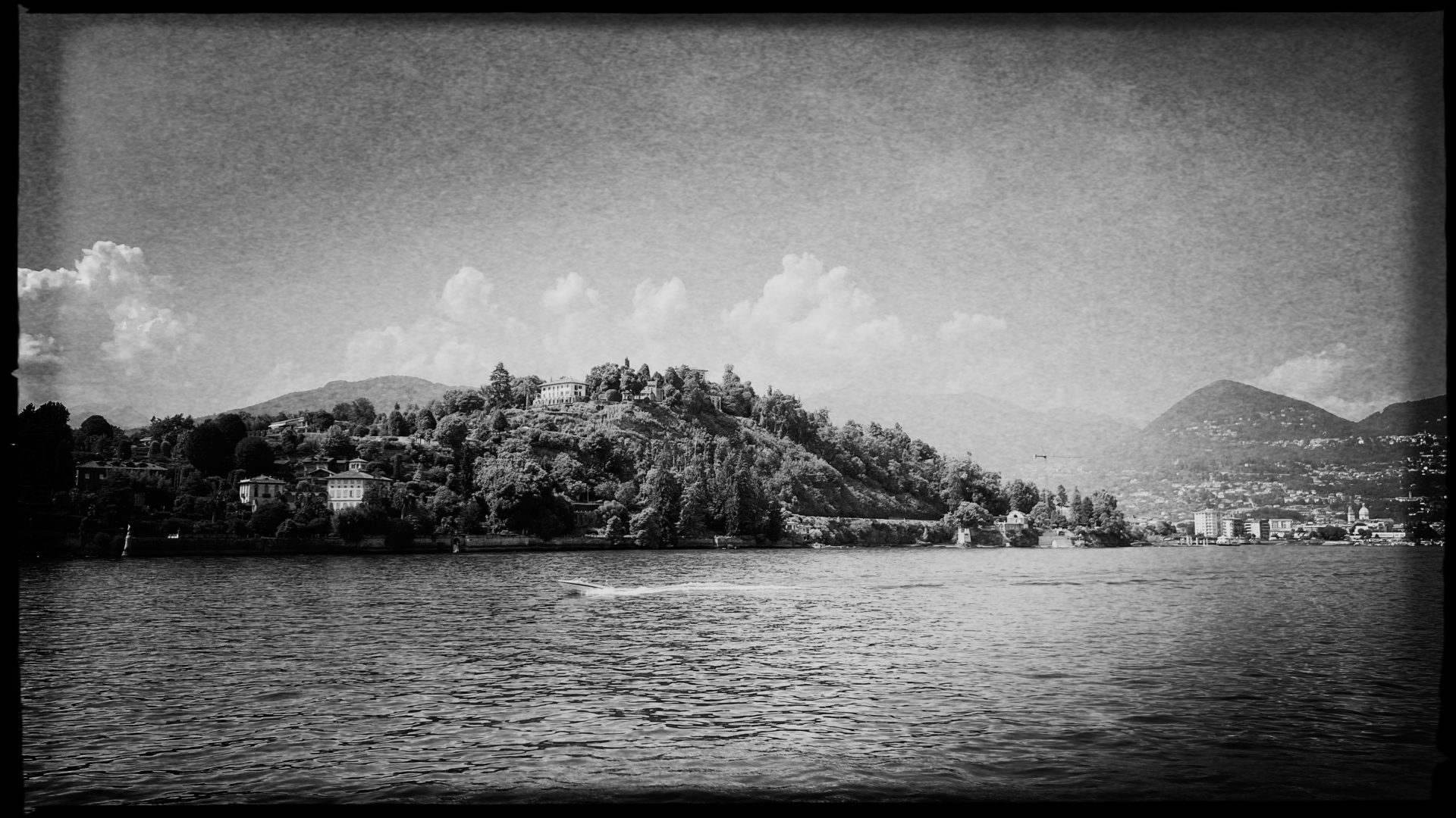Motorboot auf dem Lago Maggiore mit stattlichen Villen auf den Hügeln am Ufer