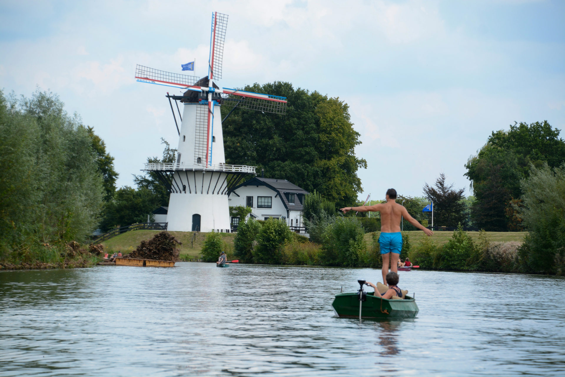 Mann in Ruderboot zeigt auf eine Windmühle
