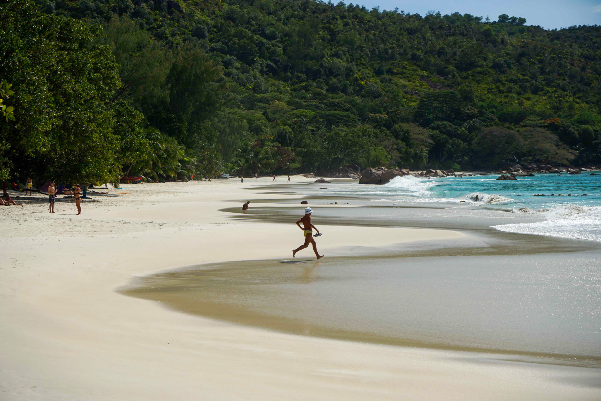Mann rennt am Strand von Praslin Anse ins Wasser