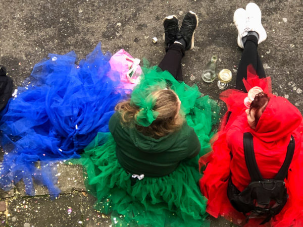 Drei angetrunkene Frauen sitzen auf dem Asphalt im Kölner Karneval